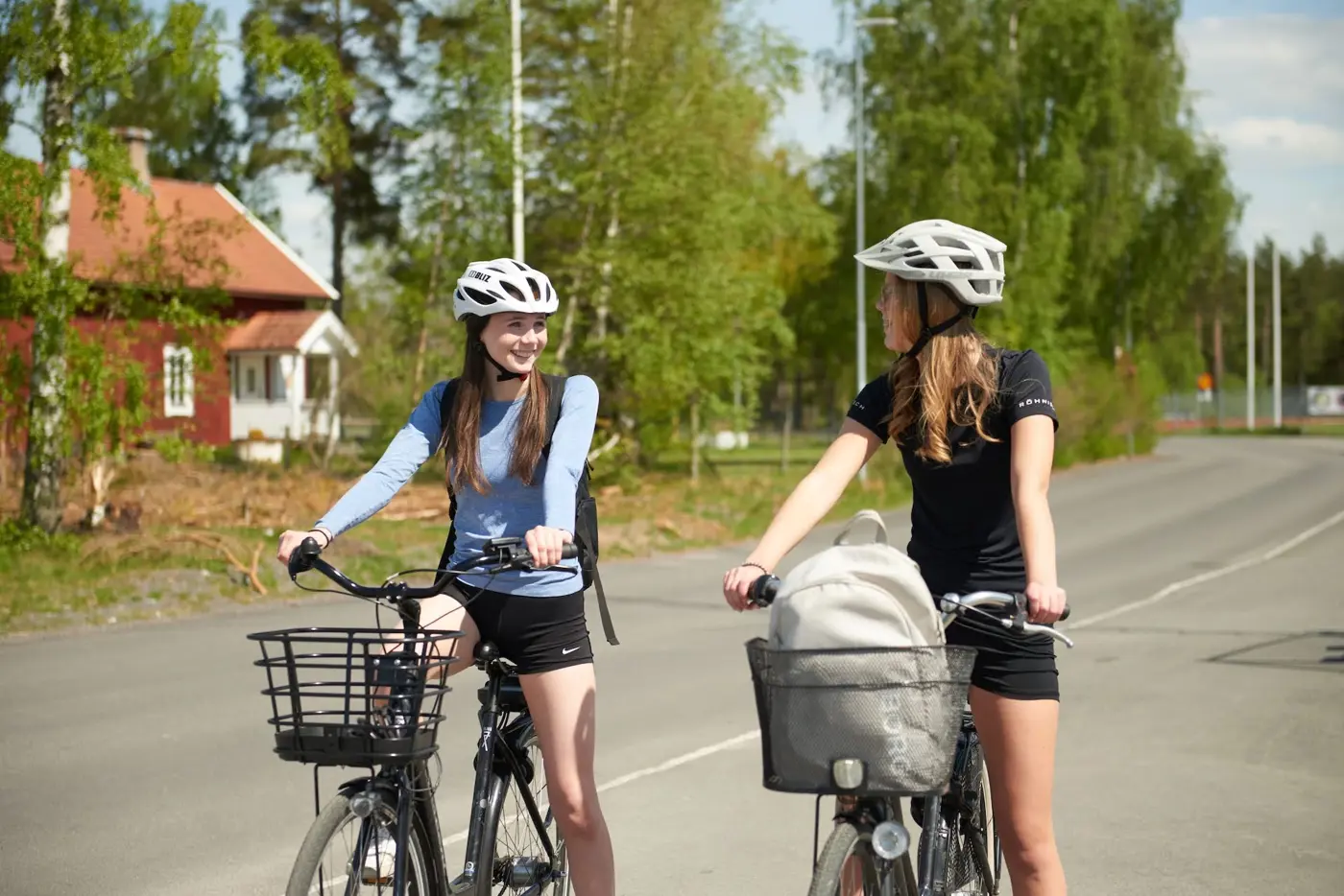 Två tonåringar sitter på varsin cykel på en asfalterad väg