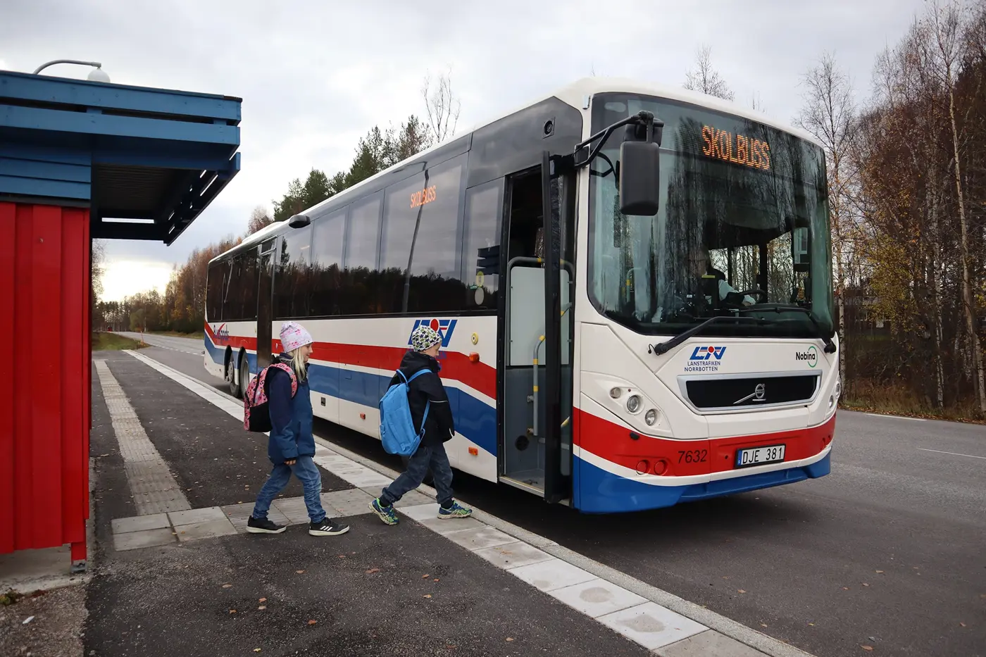 Två skolbarn är på väg att stiga på en skolbuss.