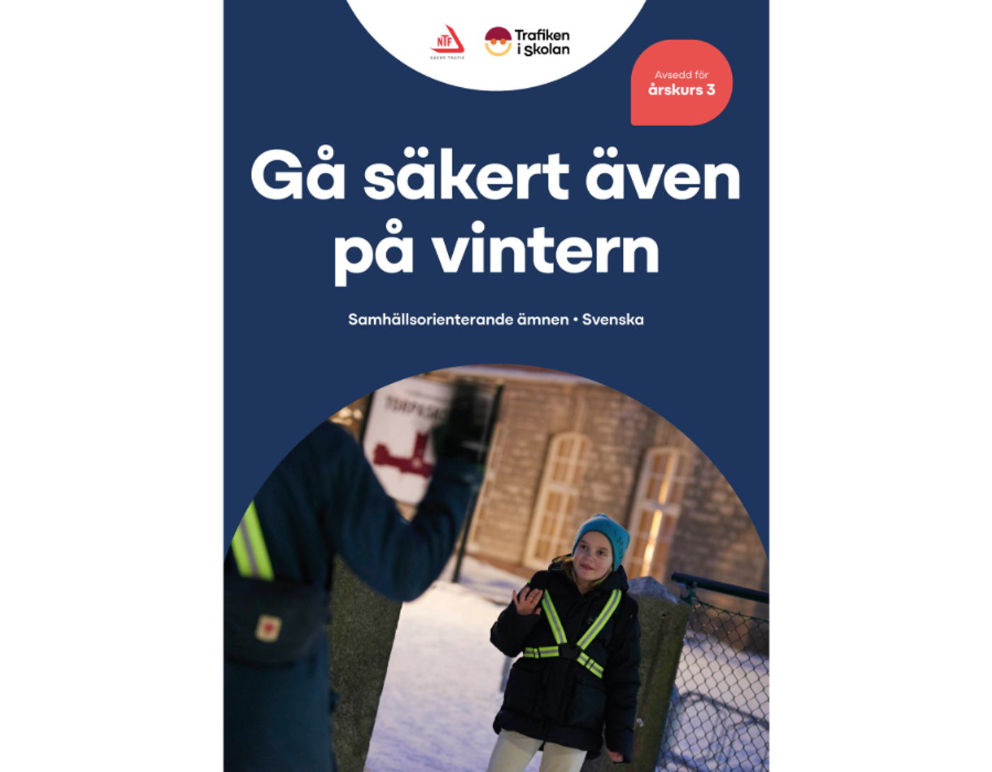 Två skolbarn med reflexväst på en snötäckt skolgård.